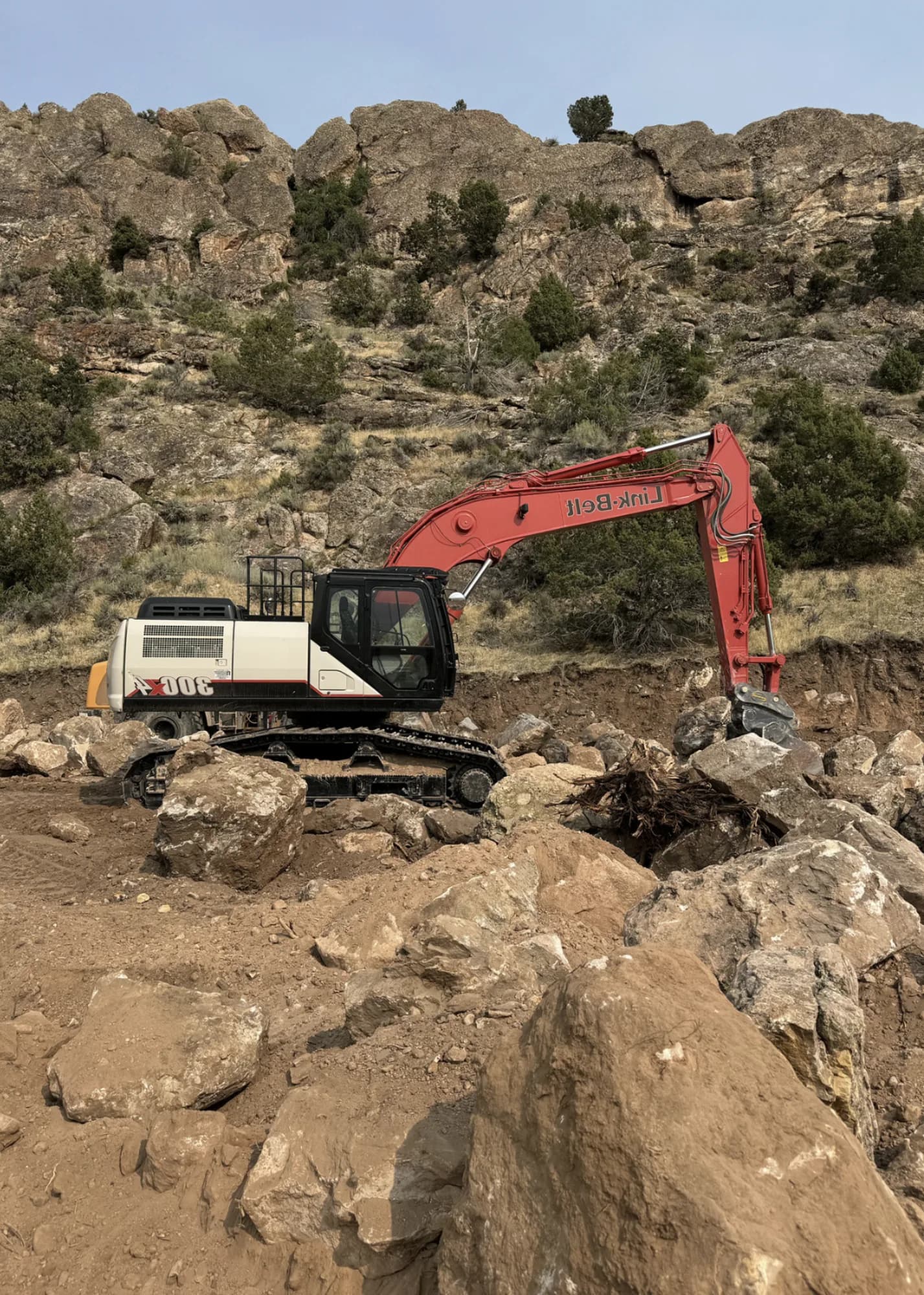 Link-Belt excavator performing excavation on rocky terrain — remote mine site
